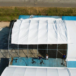 Zadaszenie kontenerowe C3340 10x12 mZadaszenie kontenerowe C3340 o wymiarach 10×12 m dostępne na inamiot.pl to ekonomiczne, trwałe i wszechstronne rozwiązanie magazynowe, które doskonale sprawdza się w ochronie towarów, pojazdów i maszyn przed niekorzystnymi warunkami pogodowymi. Zadaszenie to zostało zaprojektowane tak, aby zmaksymalizować przestrzeń użytkową, wykorzystując solidną, ocynkowaną na gorąco stalową konstukcję wykonaną z rur stalowych Q215 oraz wytrzymałą tkaninę PVC. Grubość tkaniny wynosi 900 g/m², co zapewnia dodatkową wytrzymałość. Zadaszenie można montować na różne sposoby, w tym przez przyspawanie do kontenera morskiego lub rozłożenie na betonowych bloczkach typu lego, ściankach oporowych oraz innych trwałych konstrukcjach. Dzięki temu zadaszenie staje się idealnym magazynem na materiały sypkie, piasek, kruszywa, pasze, nawozy, a także miejscem do sortowania śmieci czy zagrodą dla zwierząt gospodarskich.
Towar „od ręki” z dostawą w ciągu 2-3 dni na terenie Polski i 3-5 dni w Unii Europejskiej oraz montażem w 2-5 dni. Zadaszenie kontenerowe C3340 10x12 mZadaszenie kontenerowe C3340 o wymiarach 10×12 m dostępne na inamiot.pl to ekonomiczne, trwałe i wszechstronne rozwiązanie magazynowe, które doskonale sprawdza się w ochronie towarów, pojazdów i maszyn przed niekorzystnymi warunkami pogodowymi. Zadaszenie to zostało zaprojektowane tak, aby zmaksymalizować przestrzeń użytkową, wykorzystując solidną, ocynkowaną na gorąco stalową konstukcję wykonaną z rur stalowych Q215 oraz wytrzymałą tkaninę PVC. Grubość tkaniny wynosi 900 g/m², co zapewnia dodatkową wytrzymałość. Zadaszenie można montować na różne sposoby, w tym przez przyspawanie do kontenera morskiego lub rozłożenie na betonowych bloczkach typu lego, ściankach oporowych oraz innych trwałych konstrukcjach. Dzięki temu zadaszenie staje się idealnym magazynem na materiały sypkie, piasek, kruszywa, pasze, nawozy, a także miejscem do sortowania śmieci czy zagrodą dla zwierząt gospodarskich.
Towar „od ręki” z dostawą w ciągu 2-3 dni na terenie Polski i 3-5 dni w Unii Europejskiej oraz montażem w 2-5 dni.