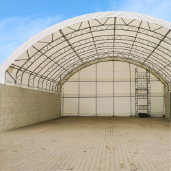 Zadaszenie pomiędzy bloki betonowe  BC4640 14,92×12,19 mZadaszenie na blokach betonowych BC4640 14,92×12,19 m – całoroczna ochrona bez fundamentów
Zadaszenie BC4640C (14,92×12,19 m) oparte na blokach betonowych to ekonomiczny i szybki sposób na stworzenie zewnętrznej, całorocznej przestrzeni magazynowej bez wykonywania stałych fundamentów. Konstrukcja wykorzystuje prefabrykowane bloki typu „lego” jako ściany oporowe, pomiędzy którymi montuje się stalowy dach z plandeką PVC. Dzięki temu zyskujesz solidne zadaszenie między blokami betonowymi, które chroni towary, pojazdy i maszyny przed deszczem, śniegiem, wiatrem i promieniowaniem UV, a jednocześnie łatwo je dopasować do układu placu.
