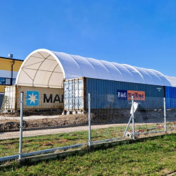Надстрешнице за контејнереКонтејнерско склониште C4060, 12 x 18 метара
Кров за контејнере C4060, димензија 12 x 18 метара, идеално је решење за предузећа која траже ефикасну заштиту свог радног простора или складишног простора. Захваљујући робусној конструкцији и висококвалитетним материјалима, надстрешница, монтирана између два транспортна контејнера, пружа поуздану заштиту од неповољних временских услова као што су киша, снег или јако сунце.
Инсталација надстрешнице C4060 12x18м 
Наша контејнерска надстрешница монтира сепомоћу монтажних ногу. То значи да се може поставити не само на кровове транспортних контејнера, већ и на бетонске блокове у Лего стилу, потпорне зидове, габионе и друге конструкције. Ово свестрано решење омогућава да се инсталира и обезбеди покривање за просторе на центрима за рециклажу, продајним местима агрегата, складиштима песка и соли и бетонским постројењима.
Конструкција и материјали
Надстрешница за контејнере C4040, ширине 12 м и дужине 18 м, направљена је од издржљивог поцинкованог челика, што гарантује отпорност на корозију и дуг век трајања. Челична конструкција је додатно ојачана дијагоналним потпором на првом и последњем пару носећих лукова. Кров надстрешнице за контејнере направљен је од дебеле ПВЦ тканине тежине 750 г/м², која пружа одличну заштиту од воде и УВ зрачења.

